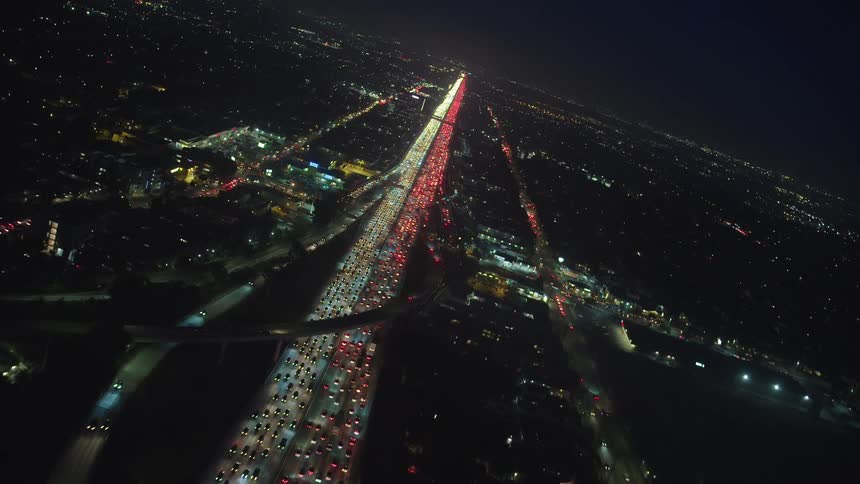 Headlights and tail lights shine and glow on a congested highway like a strip through the night