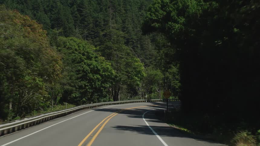 A winding road with signs and trees in the background