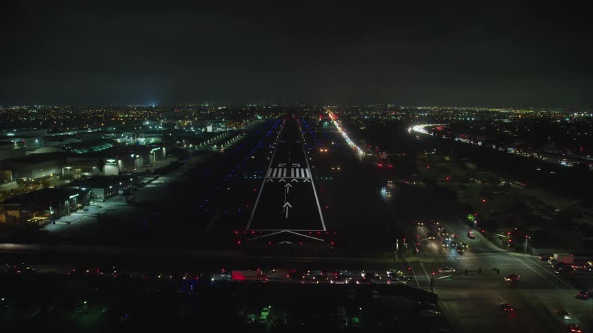 City lights and traffic driving at night as aircraft flies on to a landing strip