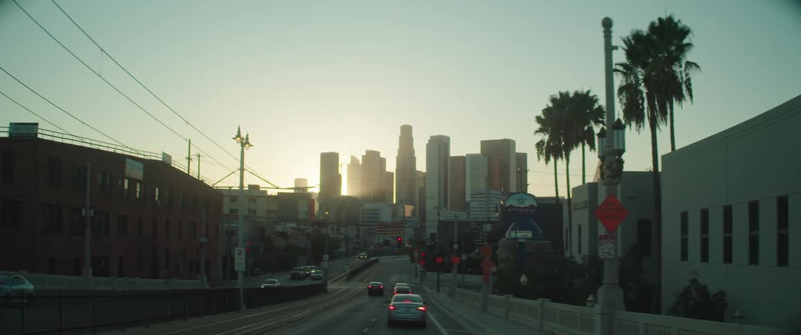 Vehicles travel a small town road towards a large city
