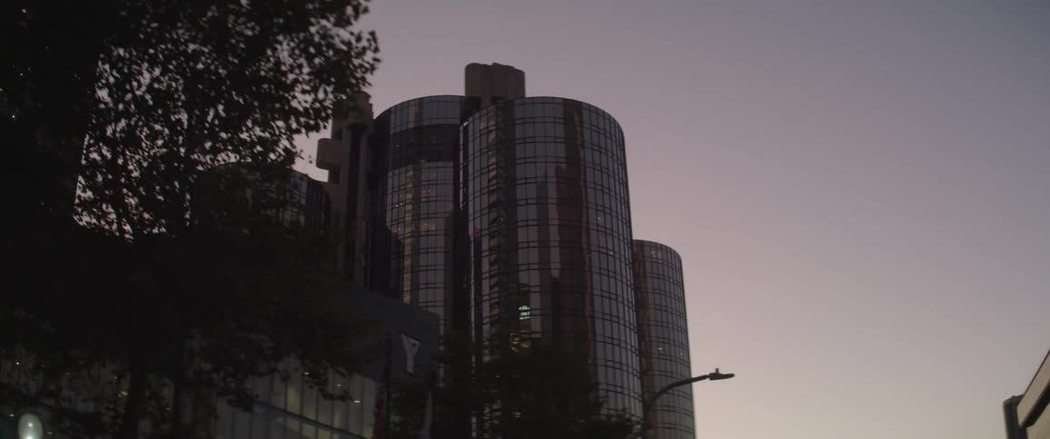 A tree line street passes by tall high rise buildings in a city