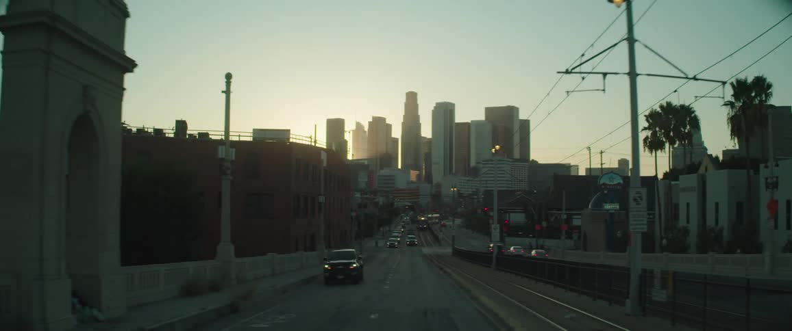 Car driving through intersection and over a bridge in the city at sunset