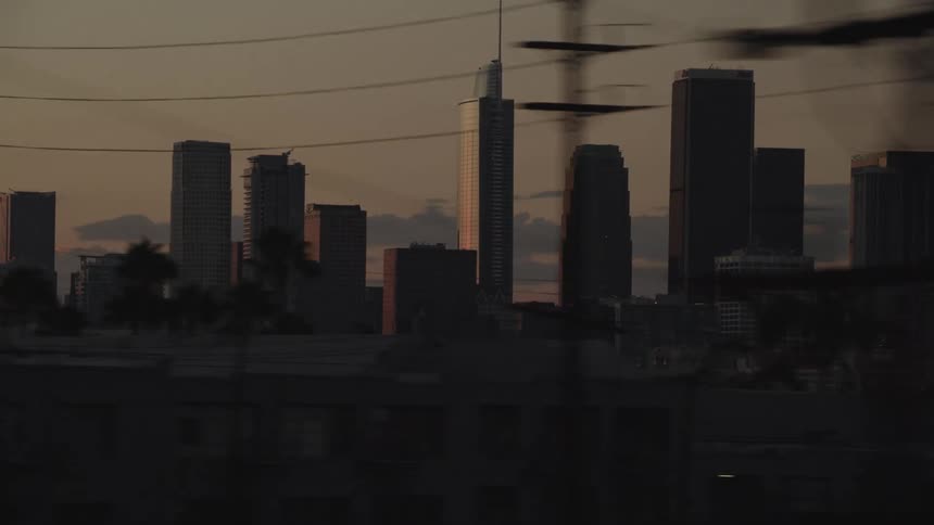 Traveling past apartment buildings in a city neighborhood with city skyline behind