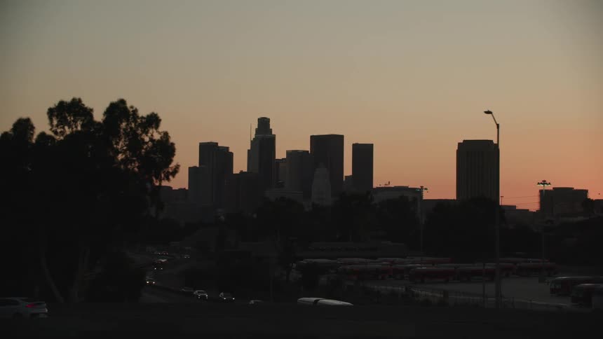 Cars driving in a city with skyscrapers in the background
