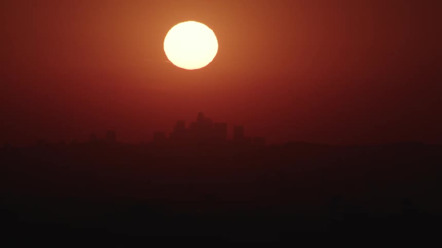 The red sun goes down behind the city