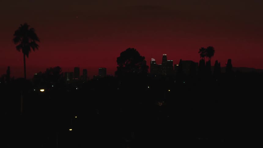 Skyline occupies middle of city sprawl at night under a red sky