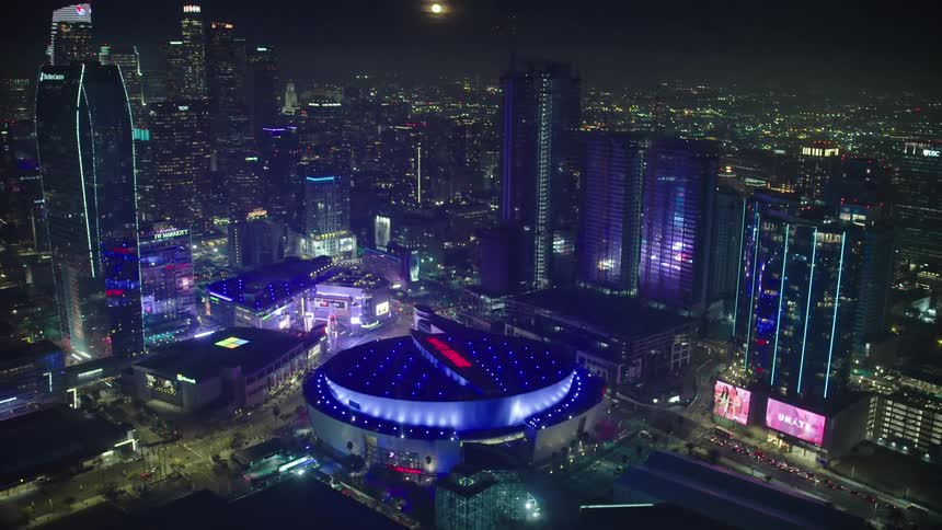 An aerial view of a downtown city is displayed at night