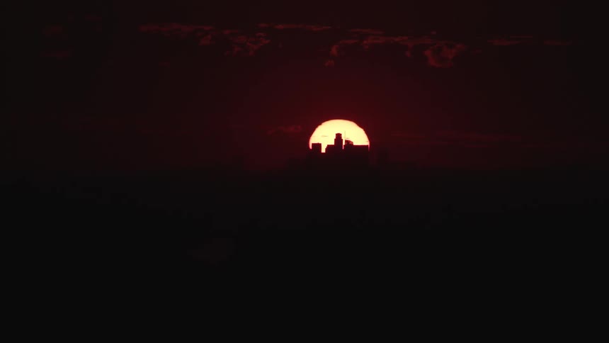 Red sun goes down behind the city