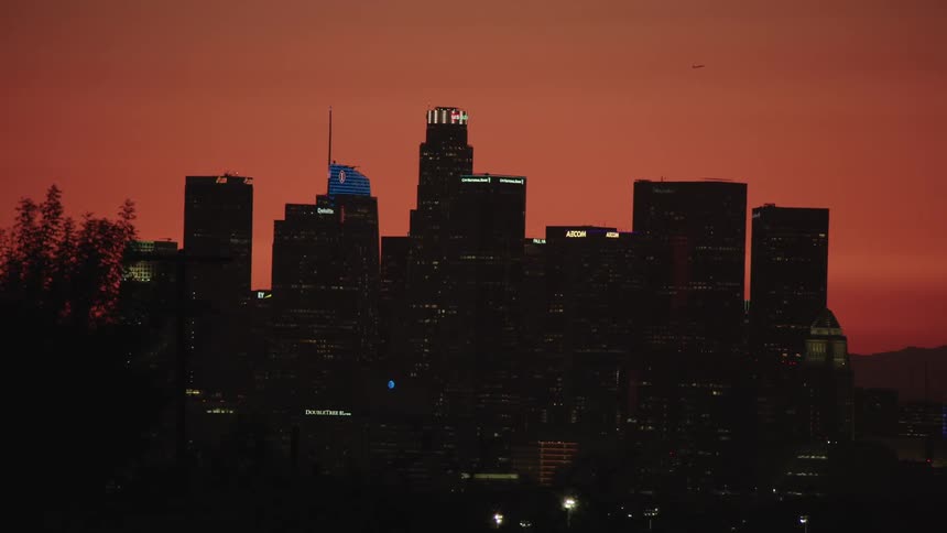 A city skyline with trees in the foreground and the sky in the background