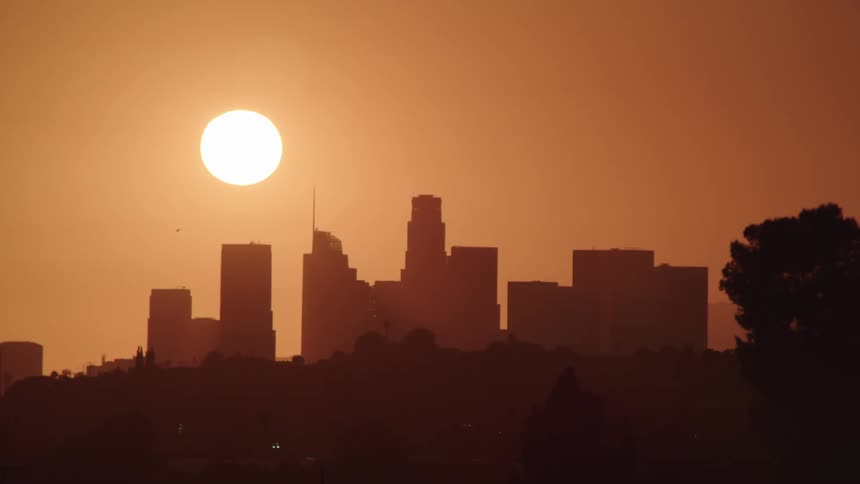 The sun silhouettes a large city skyline
