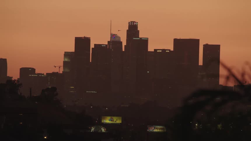 An airplane flies above skyscrapers