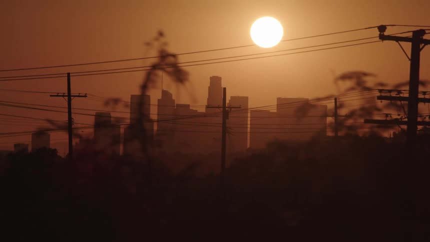 Sun turns shines high overhead turning sky over city orange