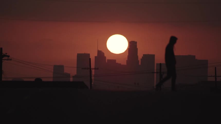 A man is walking on a road at dusk