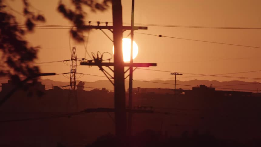 The sun rises behind a city