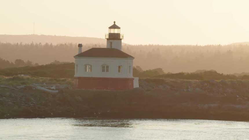House with lighthouse attached stand on shore where birds are flocking