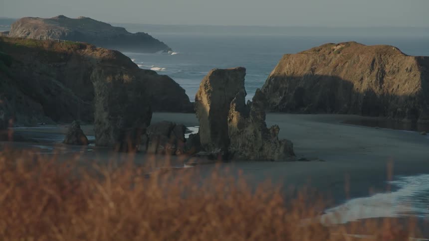 Ocean waves roll towards the rocky hills