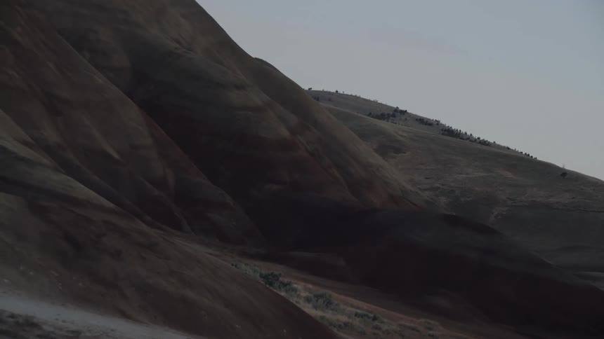 Lightly vegetated mountain slope borders scrub and sand