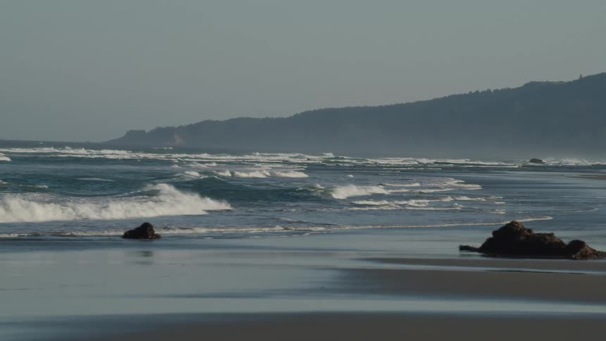 Tide rolling into a rocky beach on a foggy day