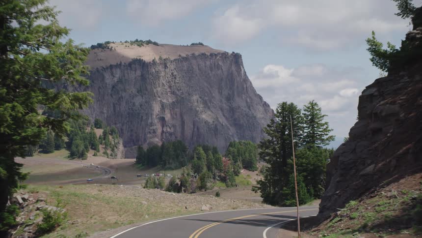 Cars drive down a winding road through the mountains