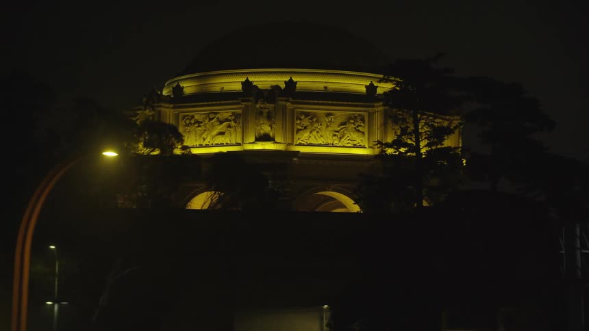 Cars travel on a highway at night passing by a lit and glowing monument