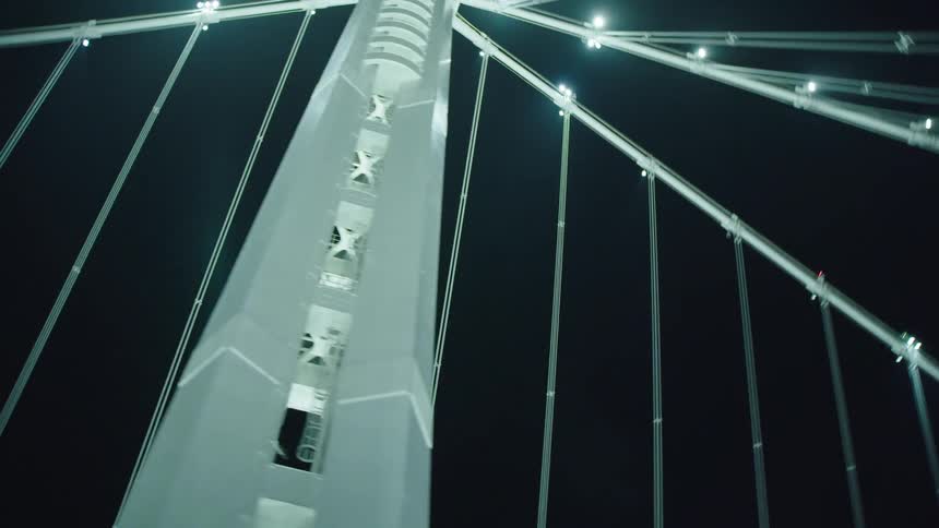 Large suspension bridge over freeway at night