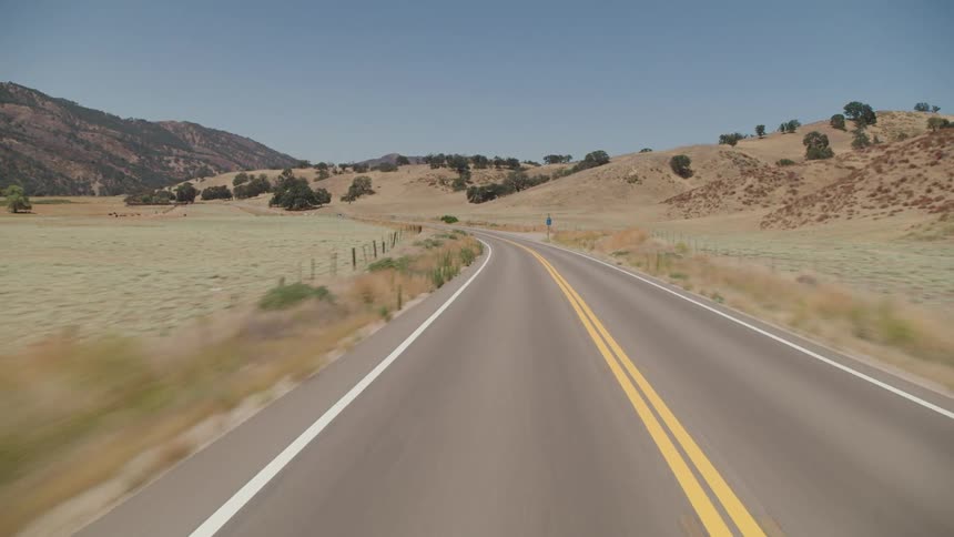 Cars are driving on a road in a rural area