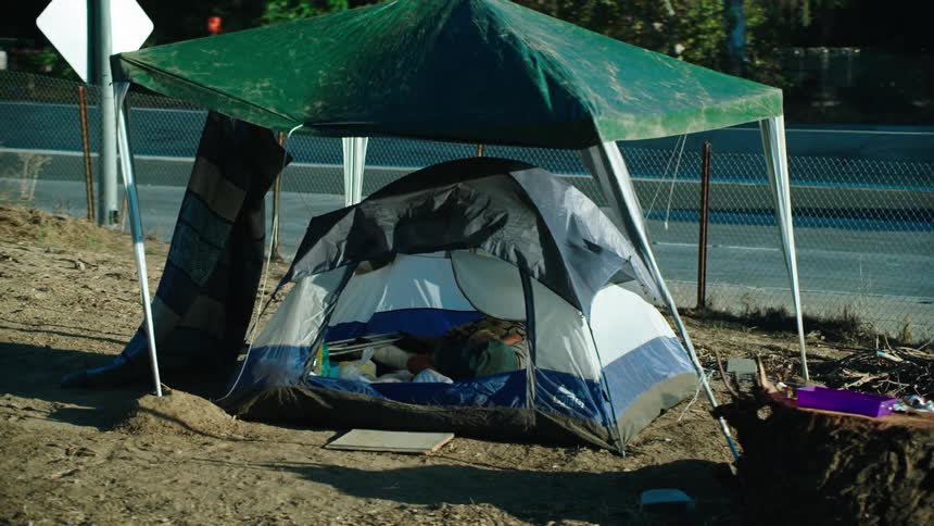 Homeless person sleeps in tent near to highway