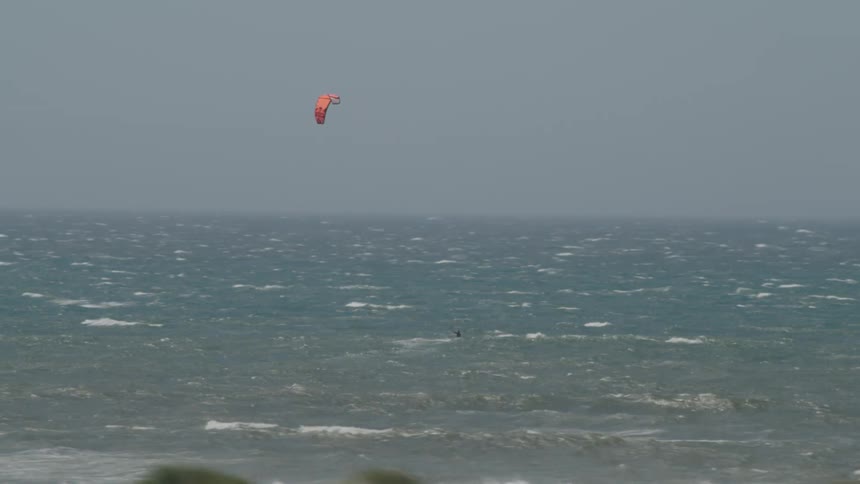 Person kite surf on ocean full of choppy waves