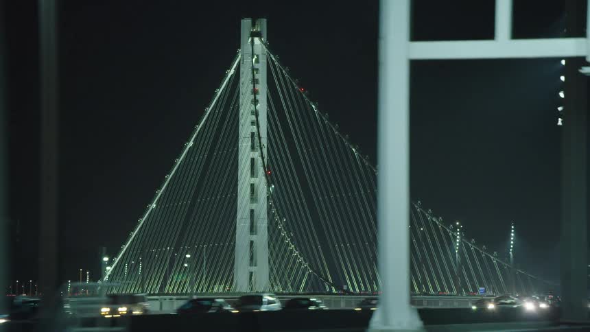 Cars are driving over a bridge at night