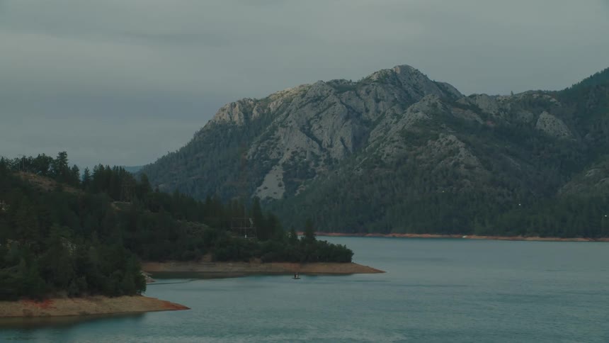 Lake surrounded by mountains covered in pine tree forest