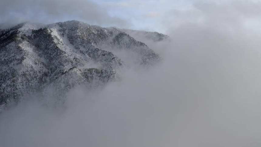 A mountain covered with snow with clouds in the foreground