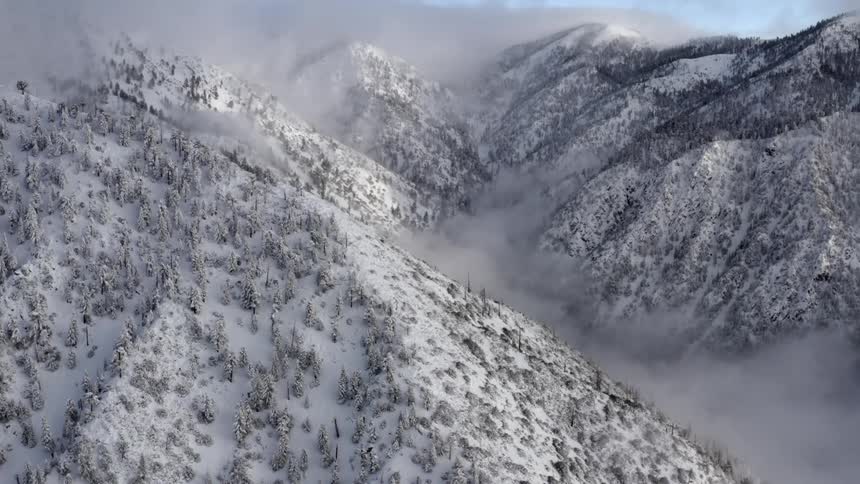 A snow covered mountain with its valleys hidden in fog