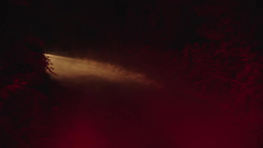 A car drives down a dusty dirt road at night