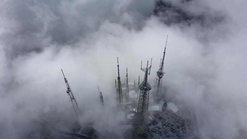 Clouds surround cluster of cell towers on snowy hill
