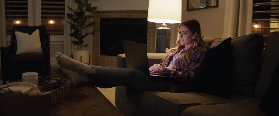 A woman sits on a couch with a laptop having a video call