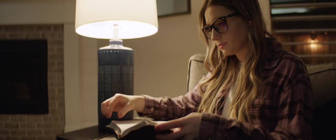 A woman sitting down in a couch reading a book
