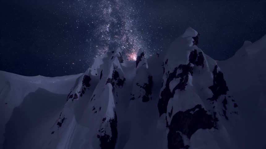 A starry sky hangs over snowy mountains