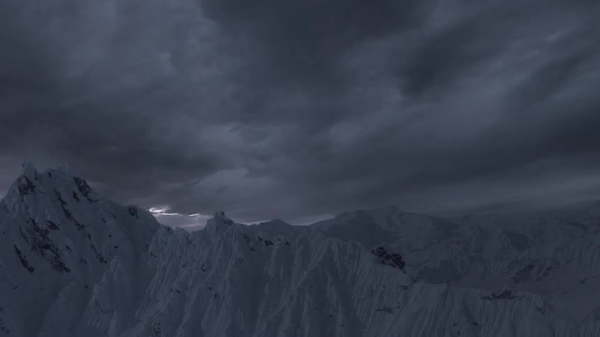 Stars in the sky above a snow covered mountain ridge fade away as the sun rises and shines brightly