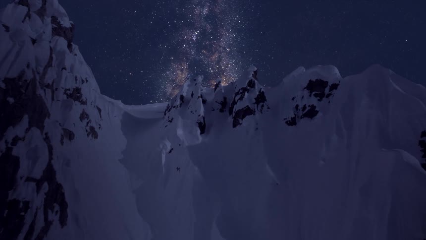A mountain covered with snow with the sky and stars in the background