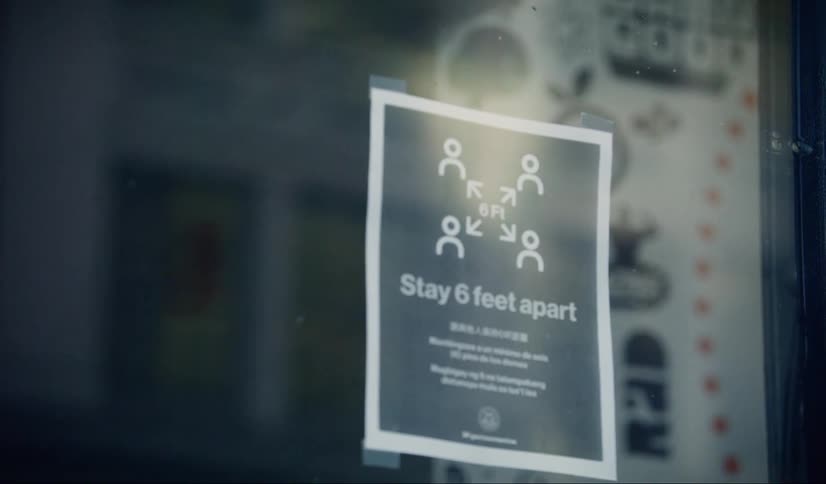 Social distancing sign on store window in city downtown