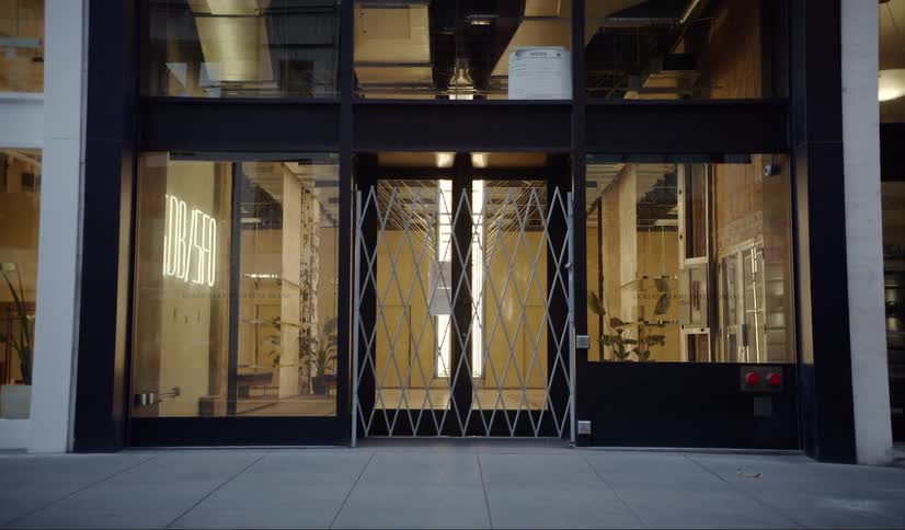 A metal gate is drawn across the entrance to a building with inside lights glowing