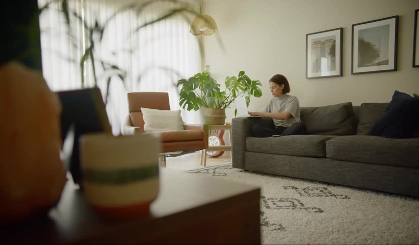 Woman sitting on the couch in the living room uses laptop during corona virus lockdown