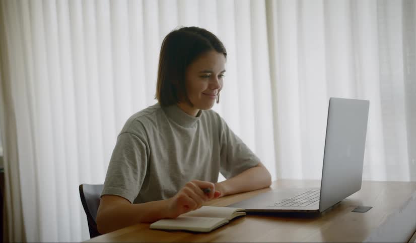 A teenager smiles at the laptop screen