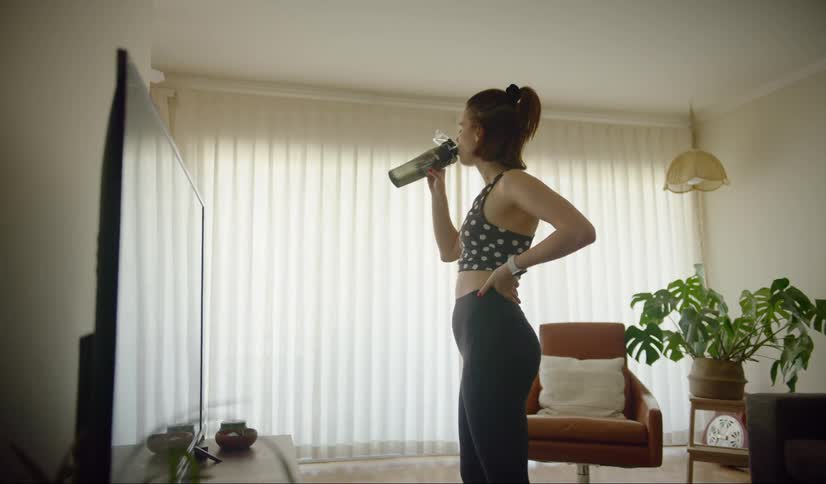 Female sips from a sports bottle in her flat