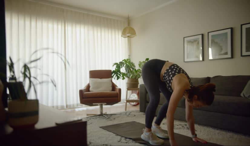 A woman putting away a water bottle and preparing to do yoga on a yoga mat