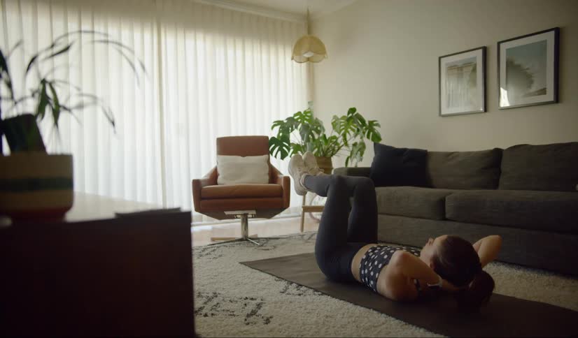 A woman is exercising on a mat in her living room