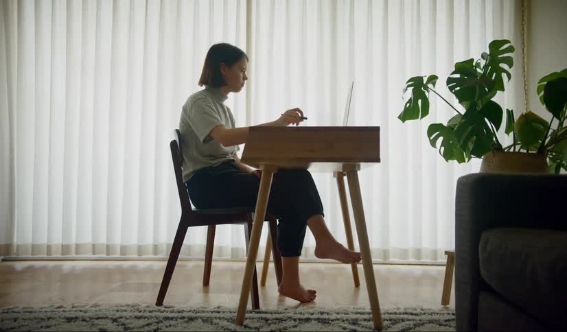 Woman sitting at the desk uses a laptop at home