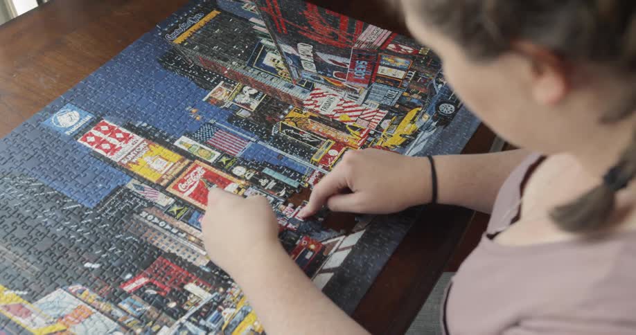 Woman sitting at the table does puzzle at home