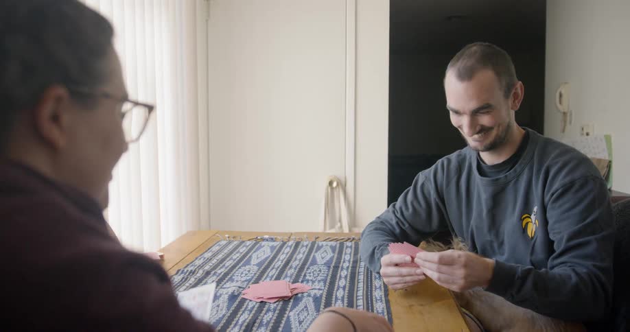 A man and woman play cards at a table