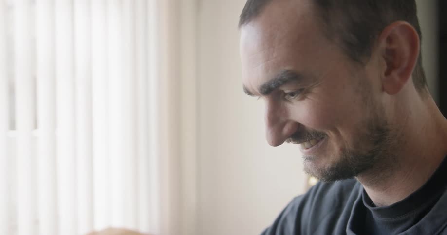 Man looks down and laughs at home